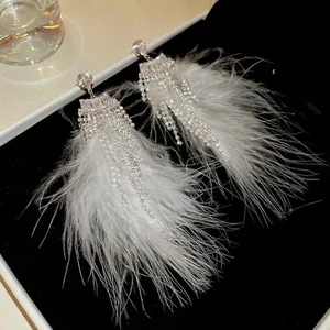 Elegant long crystal tassel and white feather drop earrings on black velvet tray