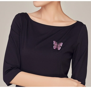 Detailed view of a purple butterfly brooch with crystals pinned on a black dress