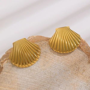 Close-up of gold shell earrings with ribbed texture on natural stone base
