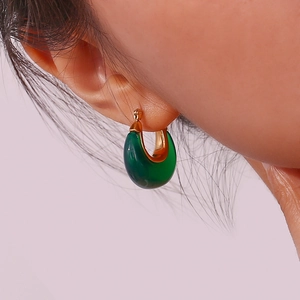 Close-up of model wearing dark green resin hoop earrings with gold-toned metallic accents