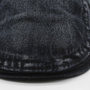 Macro shot of washed black denim fabric with double-row reinforced stitching details