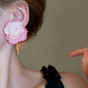 Detailed view of a handmade pink lace flower clip-on earring on a model's ear
