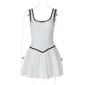 Détail de la robe blanche avec bordures noires, petit nœud et jupe plissée courte