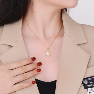Detailopname van een gouden ketting met ronde parelmoeren hanger en zonnemotief