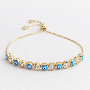 Detail view of gold adjustable evil eye bracelet with blue enamel and clear zircons