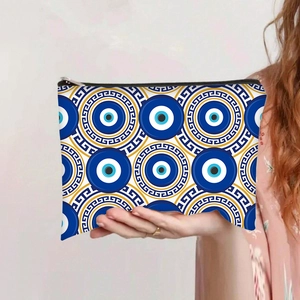 Handheld evil eye travel cosmetic bag featuring blue geometric Greek fret pattern