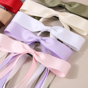 Close-up of assorted satin bow hair clips in various vibrant colors with silky texture