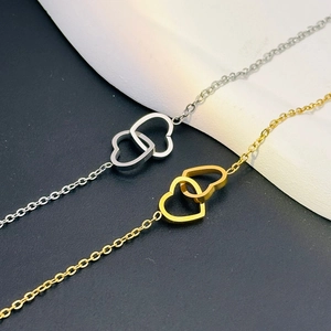 Macro detail of interlocking double heart pendants in gold and silver polished finishes