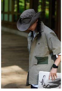 Detail of grey outdoor sun hat with drawstring and olive green cargo shirt for camping