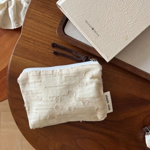 Macro view of cream cotton linen pouch with textured floral jacquard and zipper