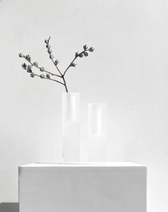 Artistic close-up of matte minimalist vases on a white pedestal with dried floral branches
