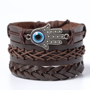 Brown leather braided bracelet with silver Hamsa Hand and blue Evil Eye charm on white background