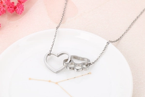 Macro detail of silver interlocking heart and cat paw pendant on a fine cross chain