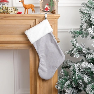Grey Christmas stocking with white faux fur trim hanging on a festive wooden mantel