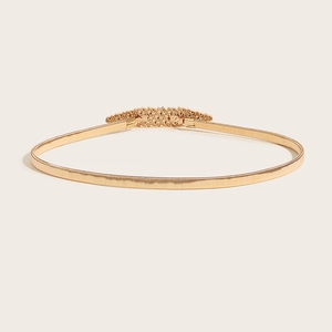 Detail of gold elastic metal spring belt featuring an intricate engraved buckle closure