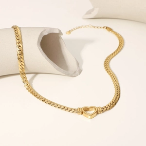 Detailed macro view of heart pendant and gold Cuban chain on minimalist white props