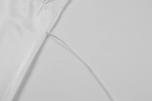 Detail of white satin dress featuring elegant stitching and delicate thin shoulder straps