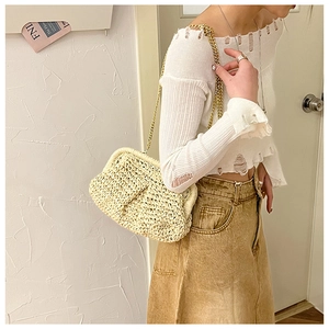 Close-up of beige woven straw clutch bag with elegant gold chain strap detail