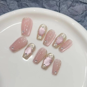 Detail of pink and gold press-on nails with cat-eye effect and rhinestone accents