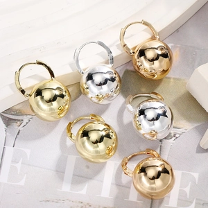Detailed view of polished sphere earrings in gold, silver, and rose gold finishes