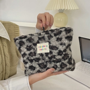 Macro detail of plush leopard print makeup bag with a white woven brand label