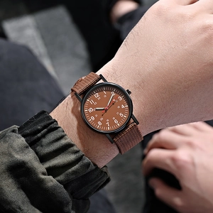Close-up of men's casual luminous watch with brown fabric strap and 24-hour dial scale