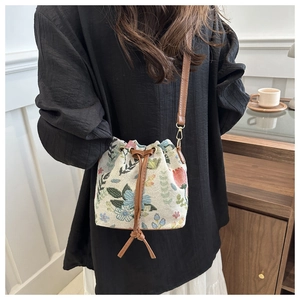 Detail of embroidered floral canvas bucket bag with brown PU leather drawstring and strap