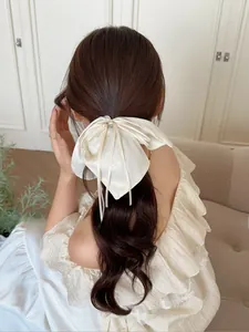 Détail du chouchou nœud blanc crème nacré avec perles et glands en ruban fluide