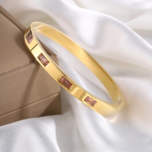 Close-up of golden stainless steel bracelet with five pink rectangular zircon stones