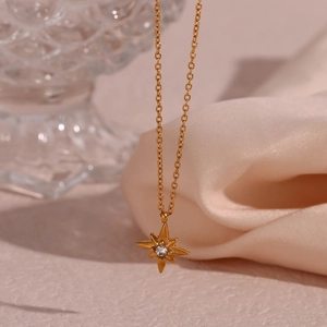 Makroansicht der goldenen Sternanhänger-Halskette mit Kristall auf rosa Seidenstoff