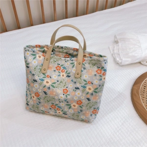 Detail of floral tote bag with brown leather handles and vintage metal rivets