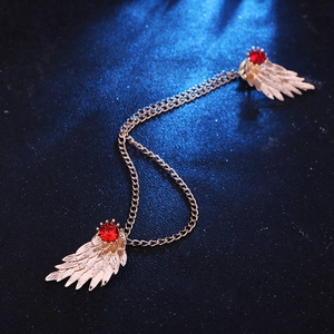 Detailed view of gold wing collar pins with red gems and elegant chain link