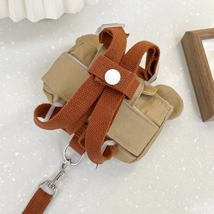 Detalle del arnés mochila de lona caqui para mascotas con correas marrones y gancho de metal