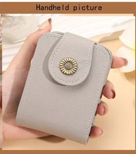 Handheld view of a mini grey cosmetic bag with sunflower buckle and mirror