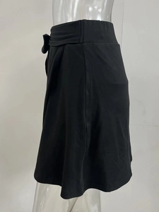 Détail d'une jupe de yoga plissée noire avec un nœud latéral et une coupe en A