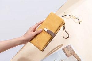 Detail of ginger frosted leather long wallet featuring leaf pattern and buckle strap