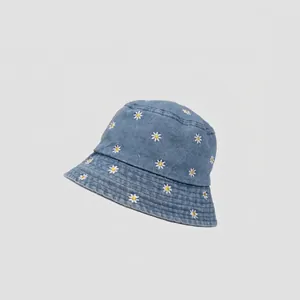 Detail of light blue denim bucket hat featuring white daisy floral embroidery pattern