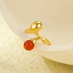 Détail d'une bague dorée 18K avec pierre rouge naturelle sur un pot en céramique