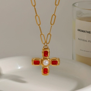 Collier croix dorée avec pierres rouges et perle sur une chaîne à gros maillons