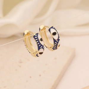 Golden hoop earrings with evil eye enamel charms hanging over a minimalist stone background