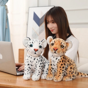 Close-up of soft plush snow leopard and leopard dolls on a wooden desk setting