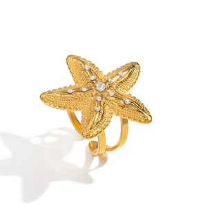 Macro view of gold starfish ring with white crystals and matte texture on white background