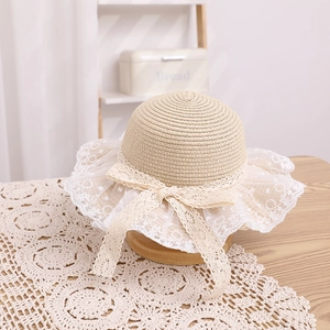 Detailed close-up of a girls' straw hat featuring layered white lace trim and a bow