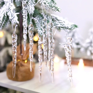 Transparent spiral icicle Christmas ornaments hanging on a snowy tree with bokeh background