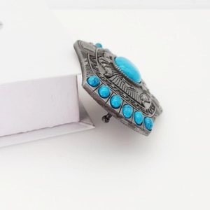 Detailed macro view of an oval Y2K bohemian belt buckle with turquoise stone inlay