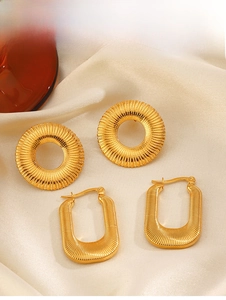 Macro view of 18K gold plated sunburst and striped geometric earrings on silk