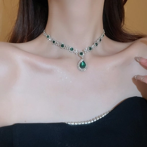 Detail of silver drop necklace with green gems and rhinestones worn by a model