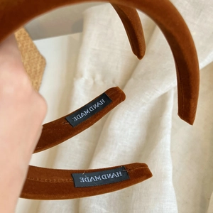 Detail of handmade velvet headband showing brown fabric texture and inner tag label