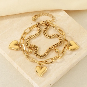 Detail of 18K gold-plated double-layer heart bracelet on a marble texture background