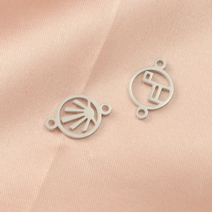 Polished stainless steel geometric sun hollow pendants on elegant pink silk backdrop